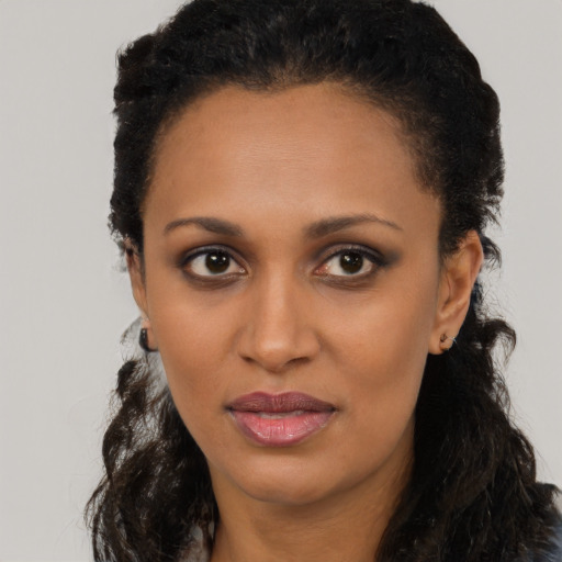 Joyful black young-adult female with long  black hair and brown eyes