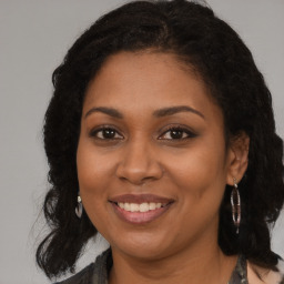 Joyful black young-adult female with long  brown hair and brown eyes