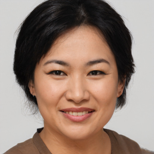 Joyful asian adult female with medium  brown hair and brown eyes