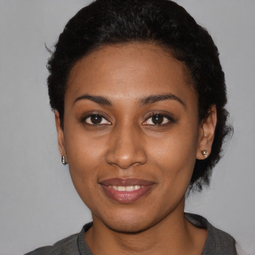 Joyful black young-adult female with short  black hair and brown eyes