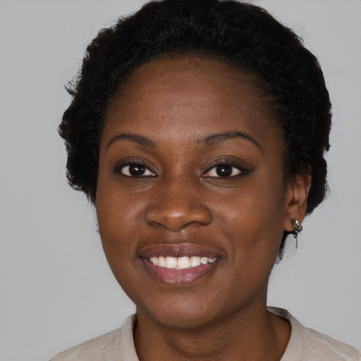 Joyful black young-adult female with short  black hair and brown eyes
