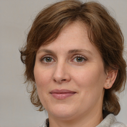 Joyful white adult female with medium  brown hair and green eyes