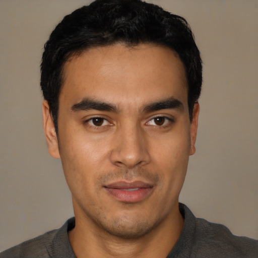 Joyful latino young-adult male with short  black hair and brown eyes
