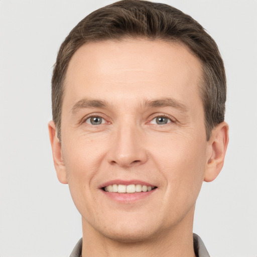 Joyful white young-adult male with short  brown hair and grey eyes