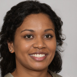 Joyful black young-adult female with long  brown hair and brown eyes