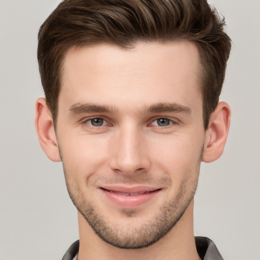 Joyful white young-adult male with short  brown hair and grey eyes