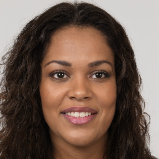 Joyful black young-adult female with long  brown hair and brown eyes
