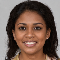 Joyful black young-adult female with long  brown hair and brown eyes