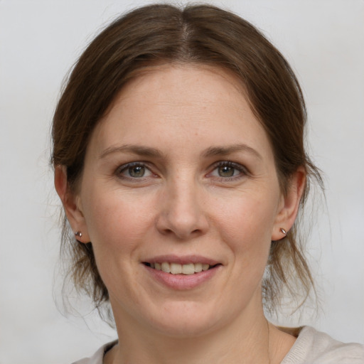 Joyful white young-adult female with medium  brown hair and grey eyes