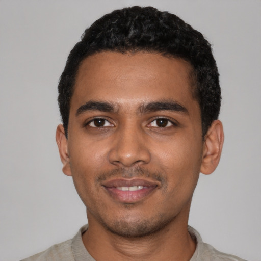 Joyful black young-adult male with short  black hair and brown eyes