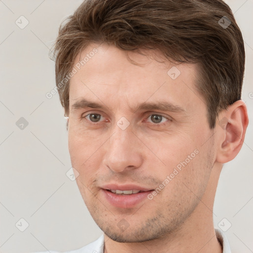 Joyful white young-adult male with short  brown hair and grey eyes