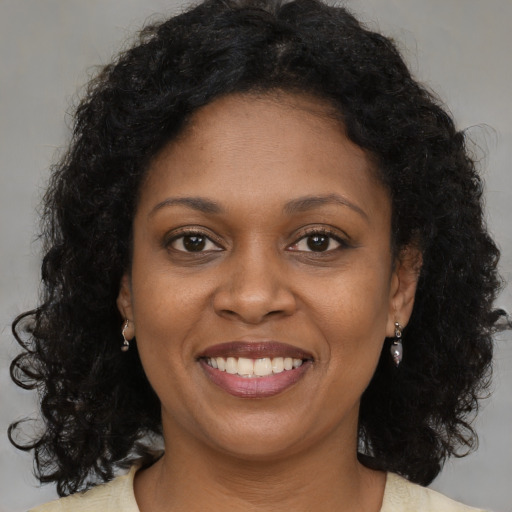 Joyful black young-adult female with long  brown hair and brown eyes