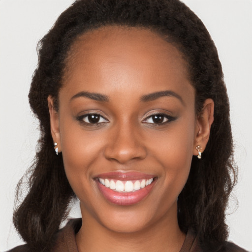 Joyful black young-adult female with long  brown hair and brown eyes