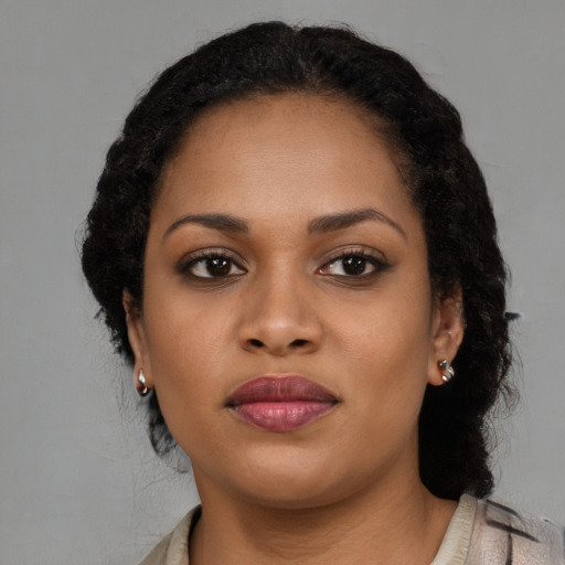 Joyful black young-adult female with long  brown hair and brown eyes