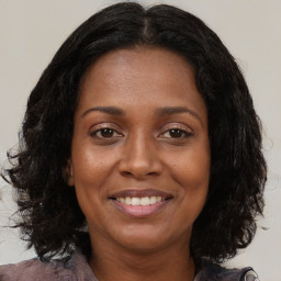 Joyful black adult female with medium  brown hair and brown eyes