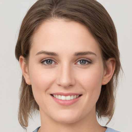 Joyful white young-adult female with medium  brown hair and grey eyes