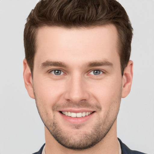 Joyful white young-adult male with short  brown hair and grey eyes