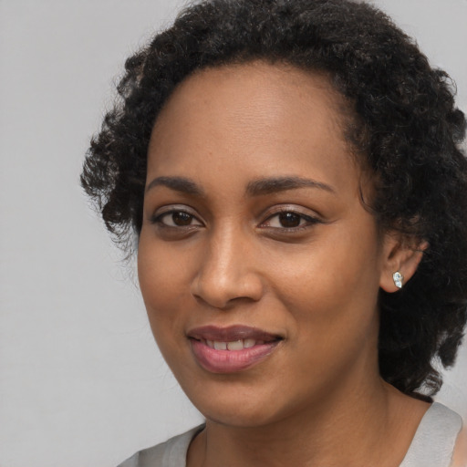 Joyful black young-adult female with long  black hair and brown eyes
