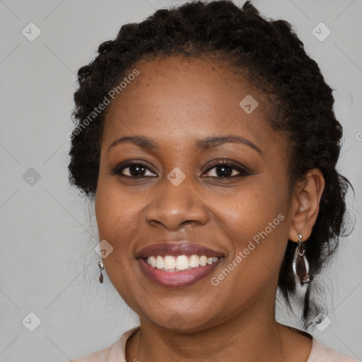 Joyful black young-adult female with long  brown hair and brown eyes