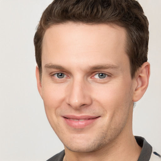 Joyful white young-adult male with short  brown hair and grey eyes