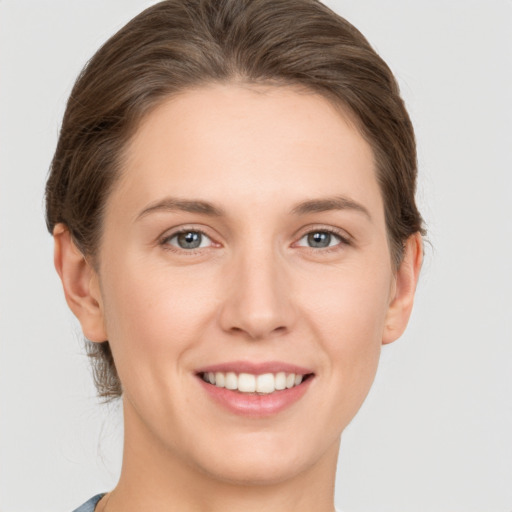 Joyful white young-adult female with medium  brown hair and grey eyes