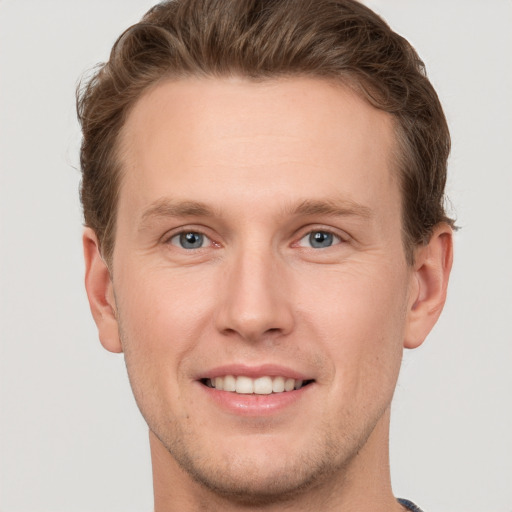 Joyful white young-adult male with short  brown hair and grey eyes