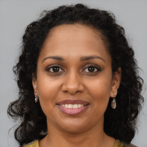 Joyful black young-adult female with long  brown hair and brown eyes