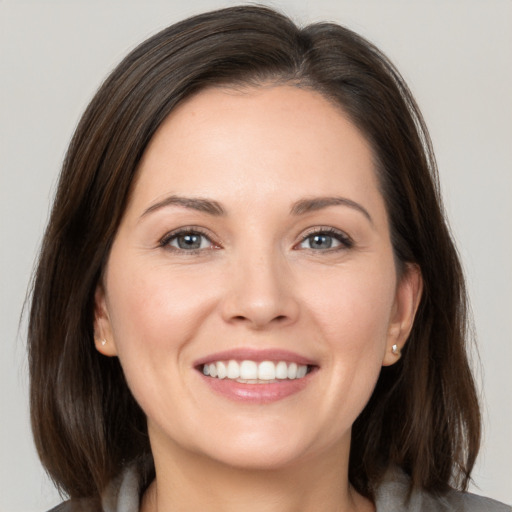 Joyful white young-adult female with medium  brown hair and grey eyes