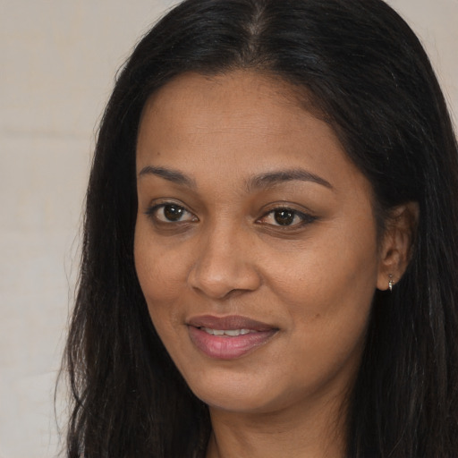 Joyful black young-adult female with long  brown hair and brown eyes