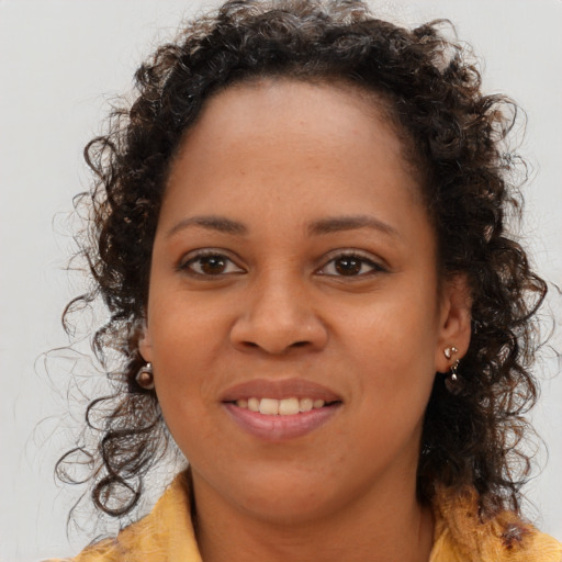 Joyful black young-adult female with long  brown hair and brown eyes