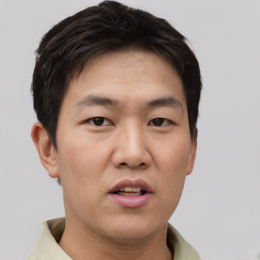 Joyful asian young-adult male with short  brown hair and brown eyes