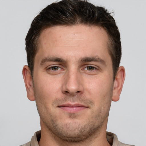 Joyful white young-adult male with short  brown hair and grey eyes