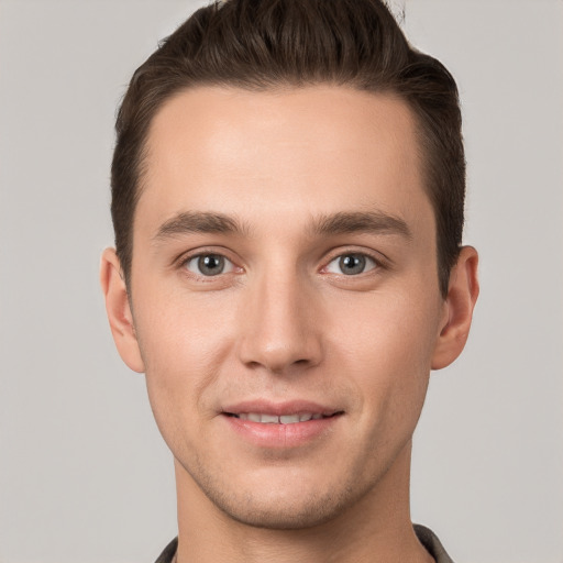 Joyful white young-adult male with short  brown hair and grey eyes