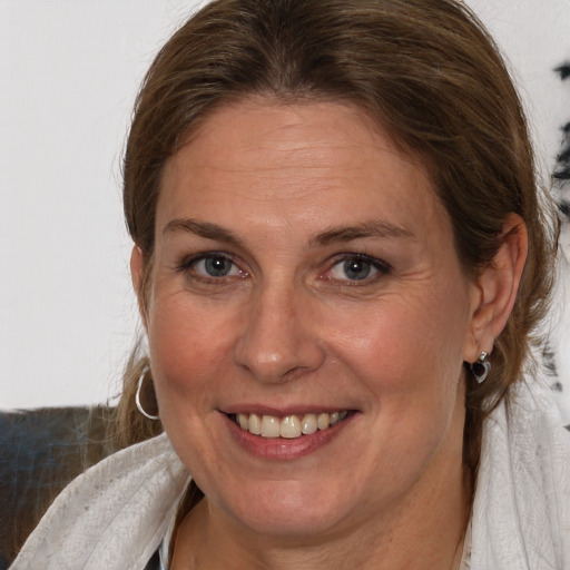 Joyful white adult female with medium  brown hair and blue eyes