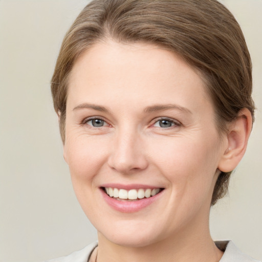 Joyful white young-adult female with medium  brown hair and grey eyes