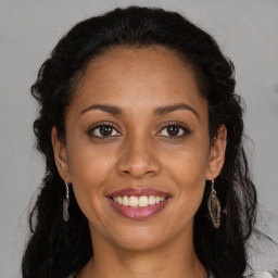 Joyful black young-adult female with long  brown hair and brown eyes