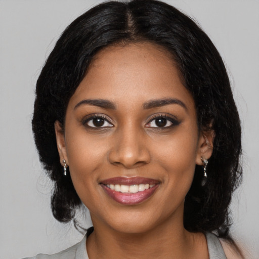 Joyful black young-adult female with long  black hair and brown eyes