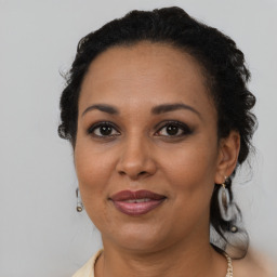 Joyful black adult female with long  brown hair and brown eyes