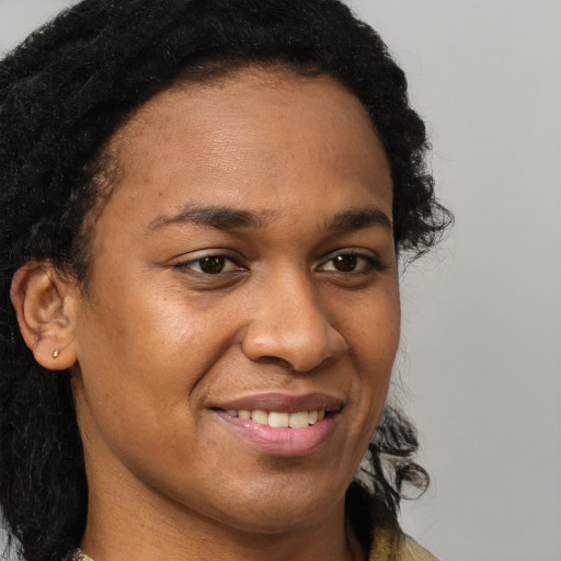 Joyful black young-adult female with long  brown hair and brown eyes