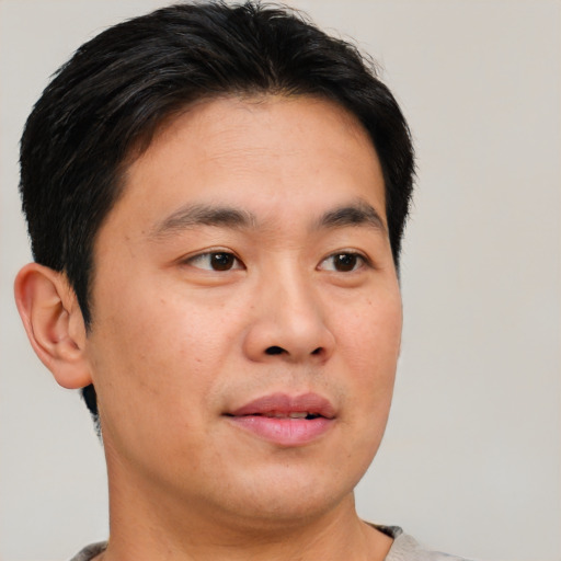 Joyful asian young-adult male with short  brown hair and brown eyes