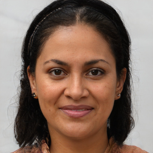 Joyful latino adult female with medium  brown hair and brown eyes