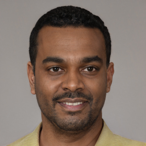 Joyful black young-adult male with short  black hair and brown eyes