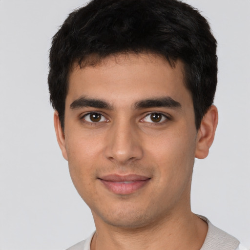 Joyful latino young-adult male with short  brown hair and brown eyes