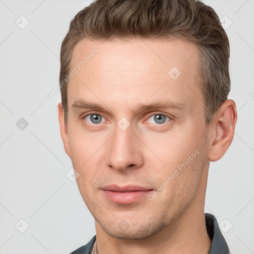 Joyful white young-adult male with short  brown hair and grey eyes