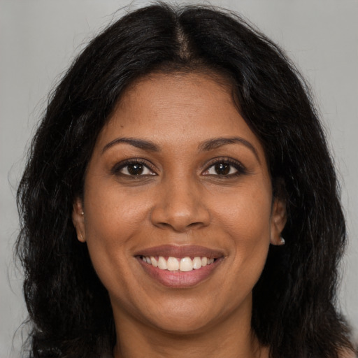 Joyful black adult female with long  brown hair and brown eyes
