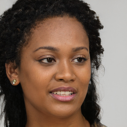 Joyful black young-adult female with long  brown hair and brown eyes