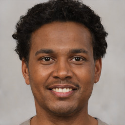 Joyful black young-adult male with short  brown hair and brown eyes
