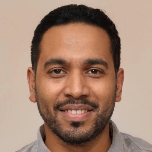 Joyful black young-adult male with short  black hair and brown eyes