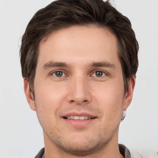 Joyful white young-adult male with short  brown hair and grey eyes