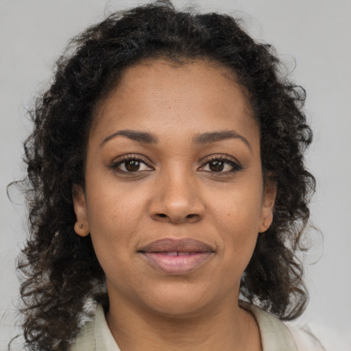 Joyful black young-adult female with long  brown hair and brown eyes